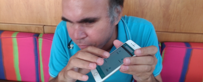 Pessoa com blusa azul, segura um aparelho celular enquanto toca na tela